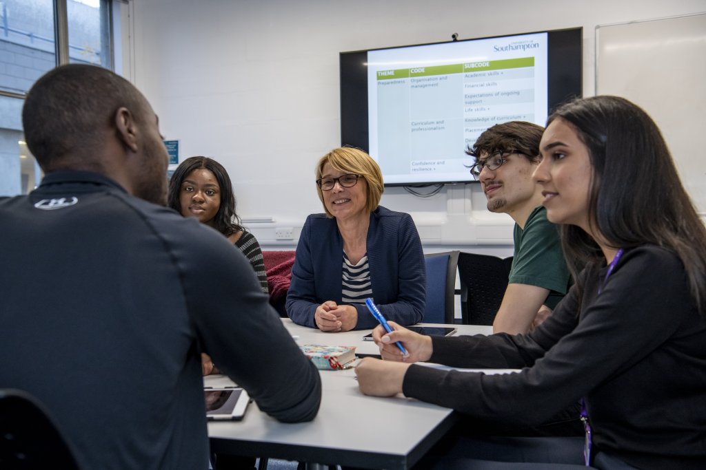 Sally is pictured sitting at a table with a diverse group of students