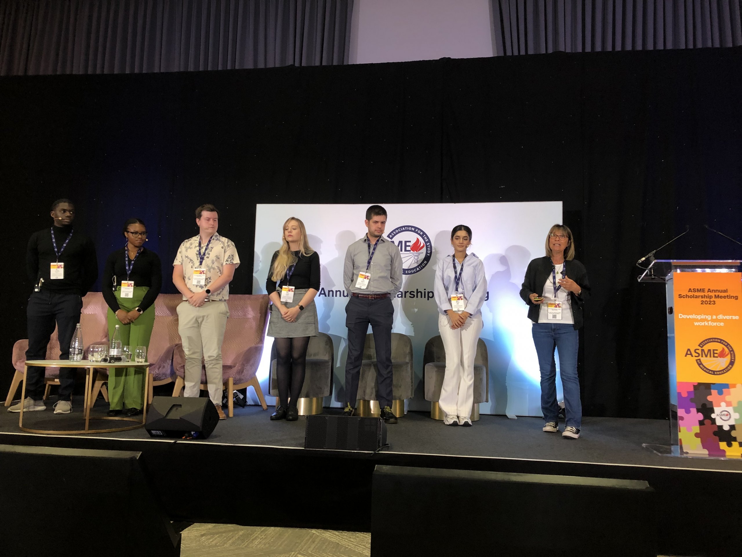 Prof Sally Curtis is speaking at the ASME conference, with six students standing on stage alongside her.